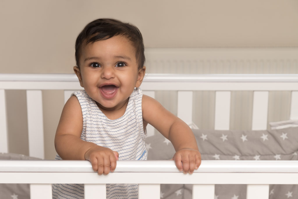 Photo of smiling baby girl in her cot in Wapping, South London