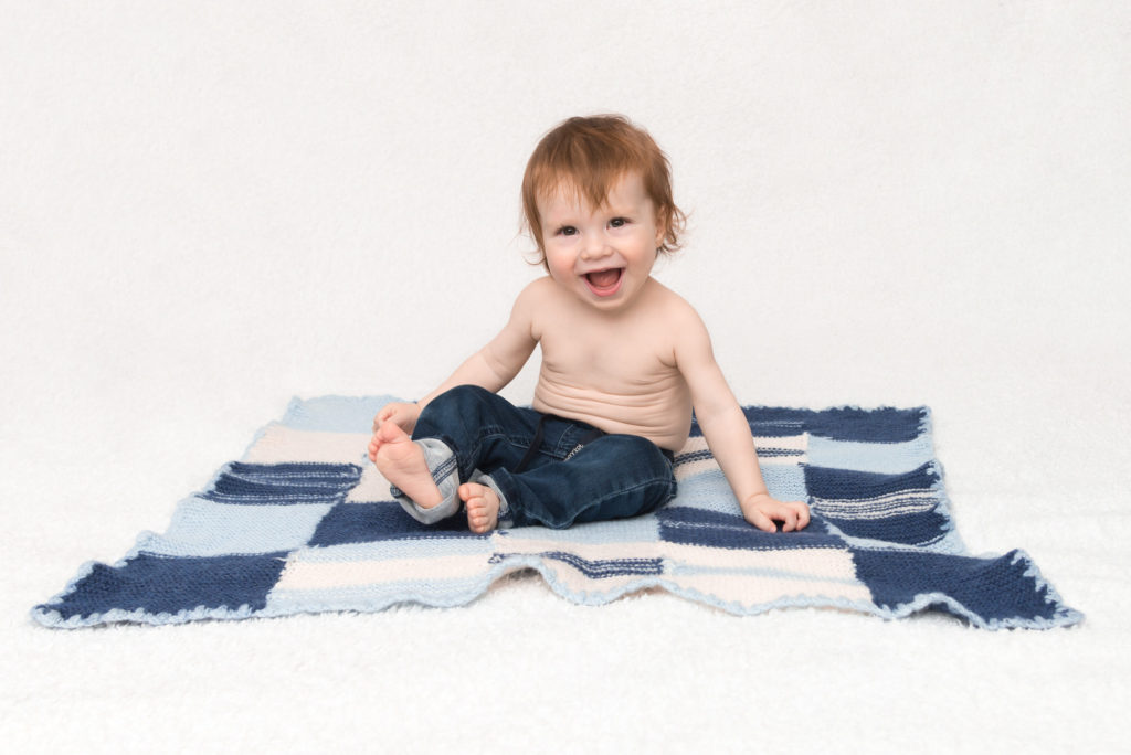 6-month old baby giggles on rug at professional photo session in Wimbledon, South London