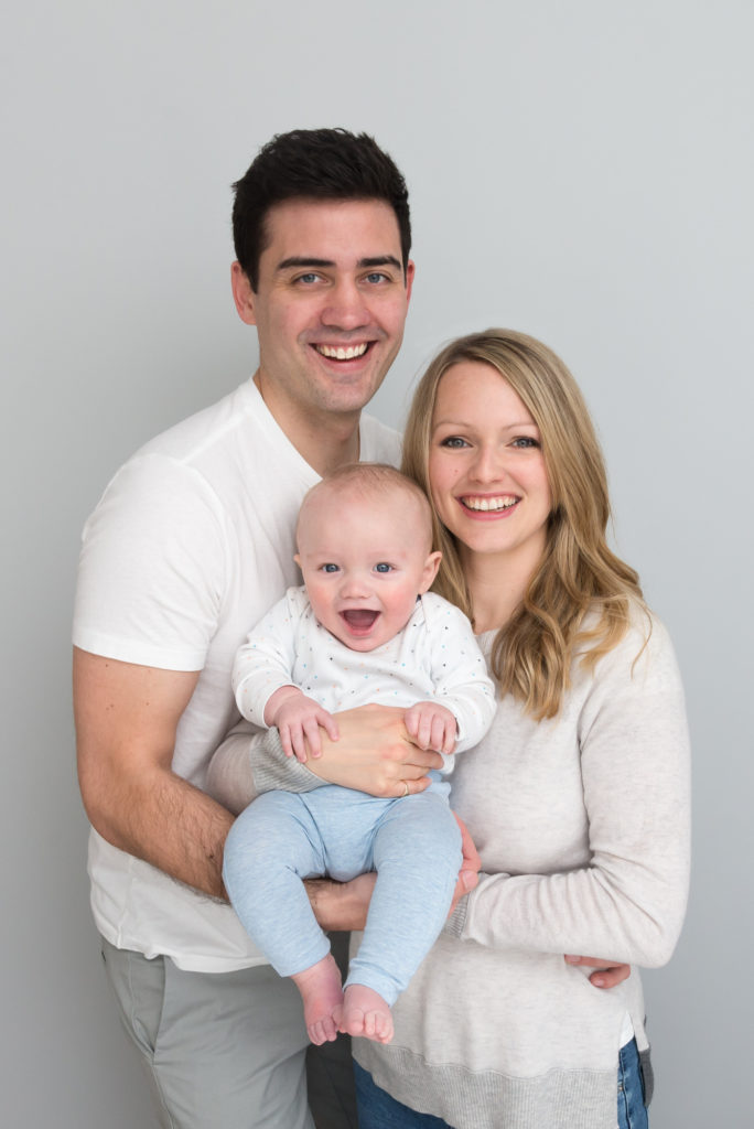 Family photography session: parents holding smiling 6 month old baby in Rotherhithe, East London