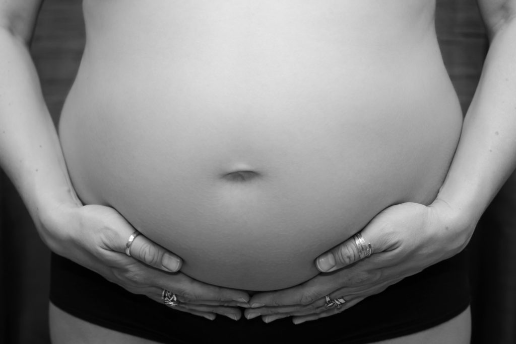 Hands underneath baby bump at a pregnancy/ maternity photoshoot in Clapham, South West London