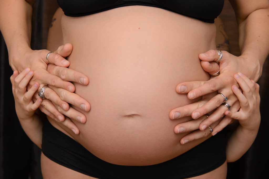 South London maternity photographer takes image of family and child hands on bump in Wapping