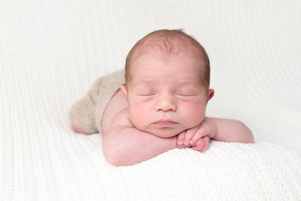 Baby sleeping on hands at newborn photoshoot at home in East London's Canary Wharf