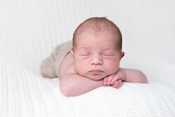 London in-home photo of newborn baby sleeping on tummy with arms under chin