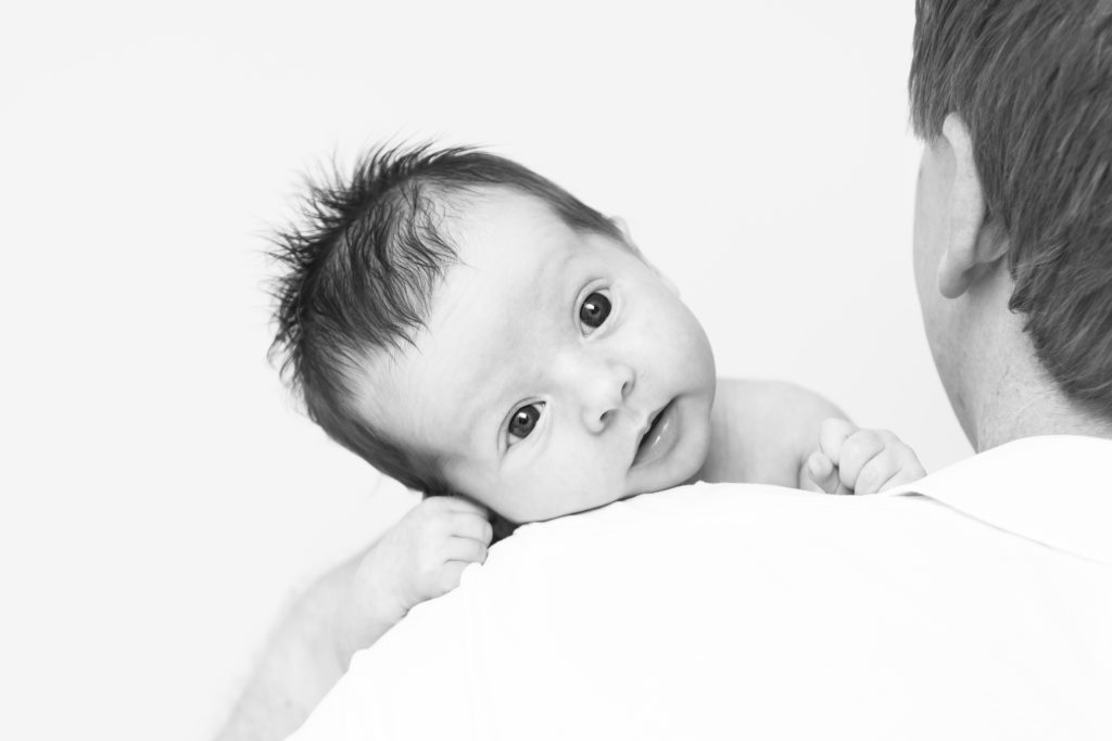 South West London newborn photographer captures black and white image of baby over mum's shoulder