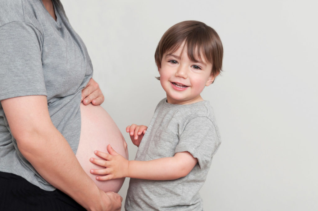 South London maternity photographer takes image of smiling boy with his hands on mummy's bump